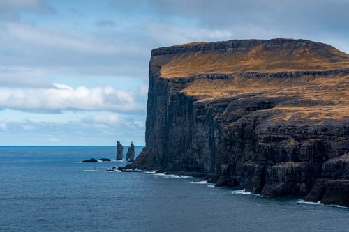 Free Stunning view of cliffs and ocean near Faroe Islands, with rugged landscape and moody sky. Stock Photo