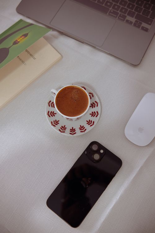 Free A warm workspace setup featuring coffee, a laptop, and a smartphone. Stock Photo