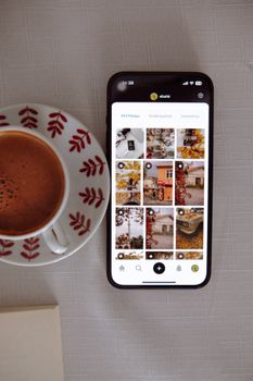 A smartphone displaying a social media app next to a cup of coffee.