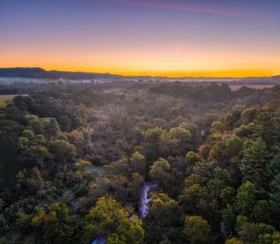 A breathtaking aerial view of Misha Mokwa's woodland during sunrise, showcasing vibrant greenery and a serene atmosphere.