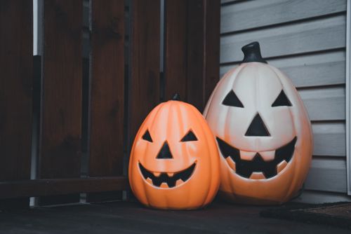 Free Two jack-o'-lantern pumpkins with carved faces symbolizing Halloween, placed in a home corner. Stock Photo