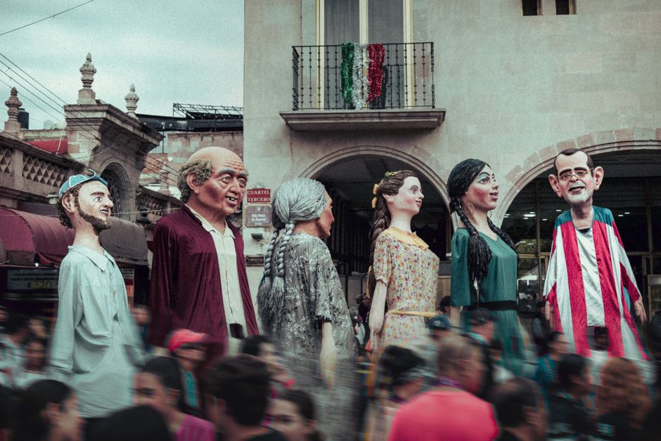 Un vibrante desfile callejero con títeres gigantes, capturando la celebración cultural en México.