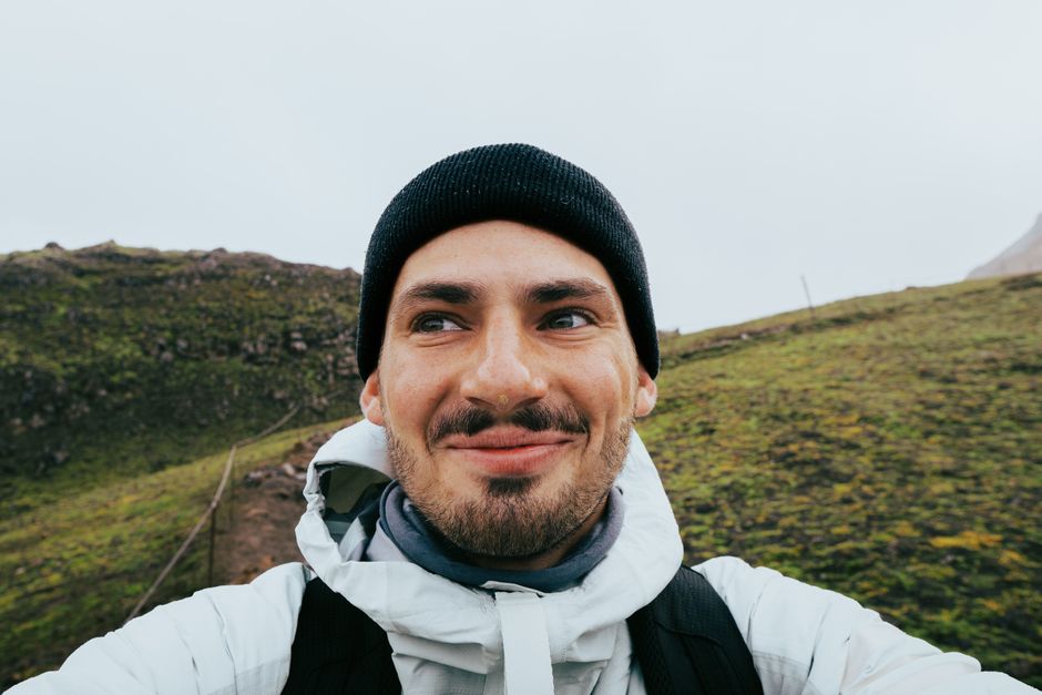 Smiling hiker in Icelandic highlands with a beanie enjoying outdoor adventure.