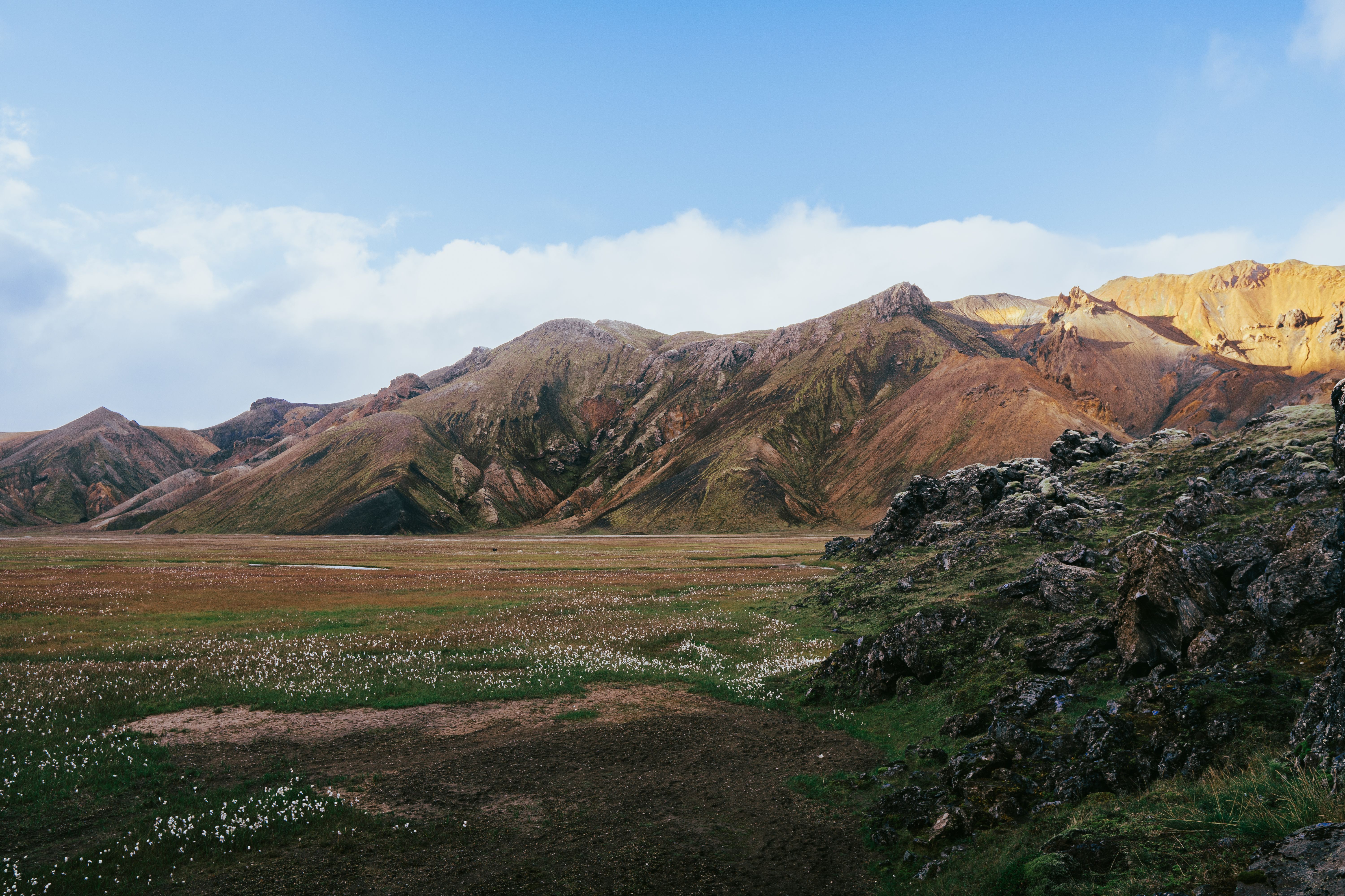 Colorful Icelandic highlands with rolling green and brown hills under dramatic clouds