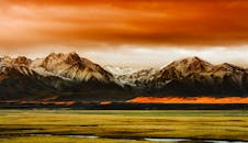 日落时分，雪山在充满活力的橙色天空下显得格外壮丽