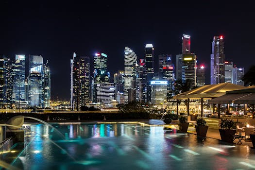 Vibrant night view of Singapore's illuminated skyline with a foreground infinity pool reflecting city lights.