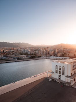 A breathtaking aerial view of Palermo, Sicily at sunrise, showcasing the serene waterfront and cityscape.