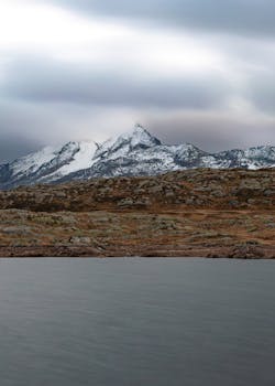 Serene view of a snow-capped mountain under a cloudy sky.