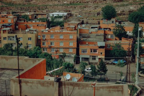 Free View of densely packed brick buildings surrounded by greenery in an urban setting. Stock Photo