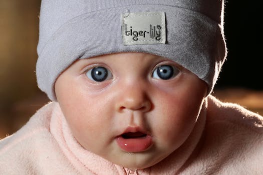Close-up portrait of a cute baby with striking blue eyes wearing a soft hat.