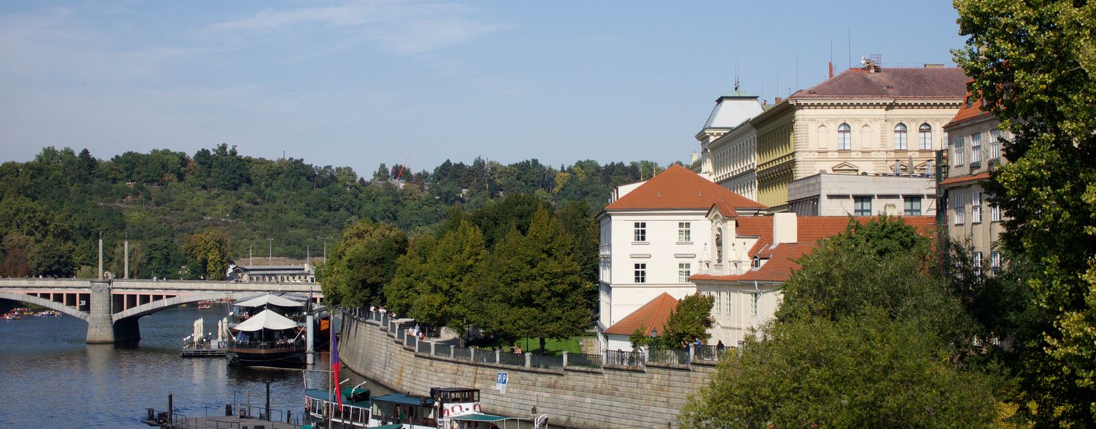 Explore the scenic riverside with historic architecture and boats in Prague, Czechia.