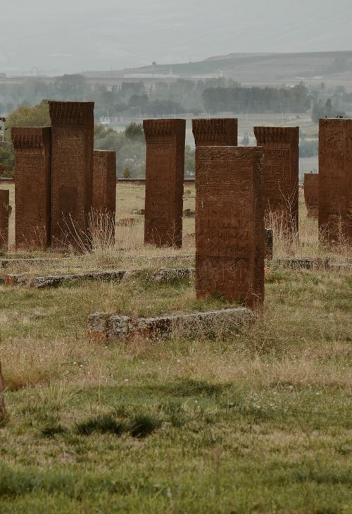 Free Rustic stone cemetery with ancient tombstones in lush green fields. Stock Photo