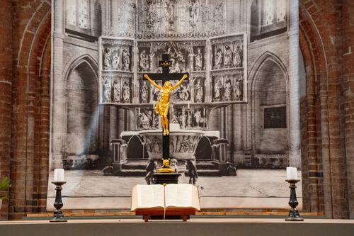 Free A detailed view of a church altar with a golden crucifix, candles, and open Bible. Stock Photo