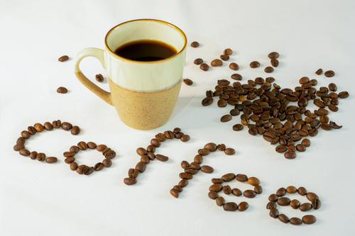 Free Creative coffee bean art with a mug on a white surface, perfect for breakfast themes. Stock Photo