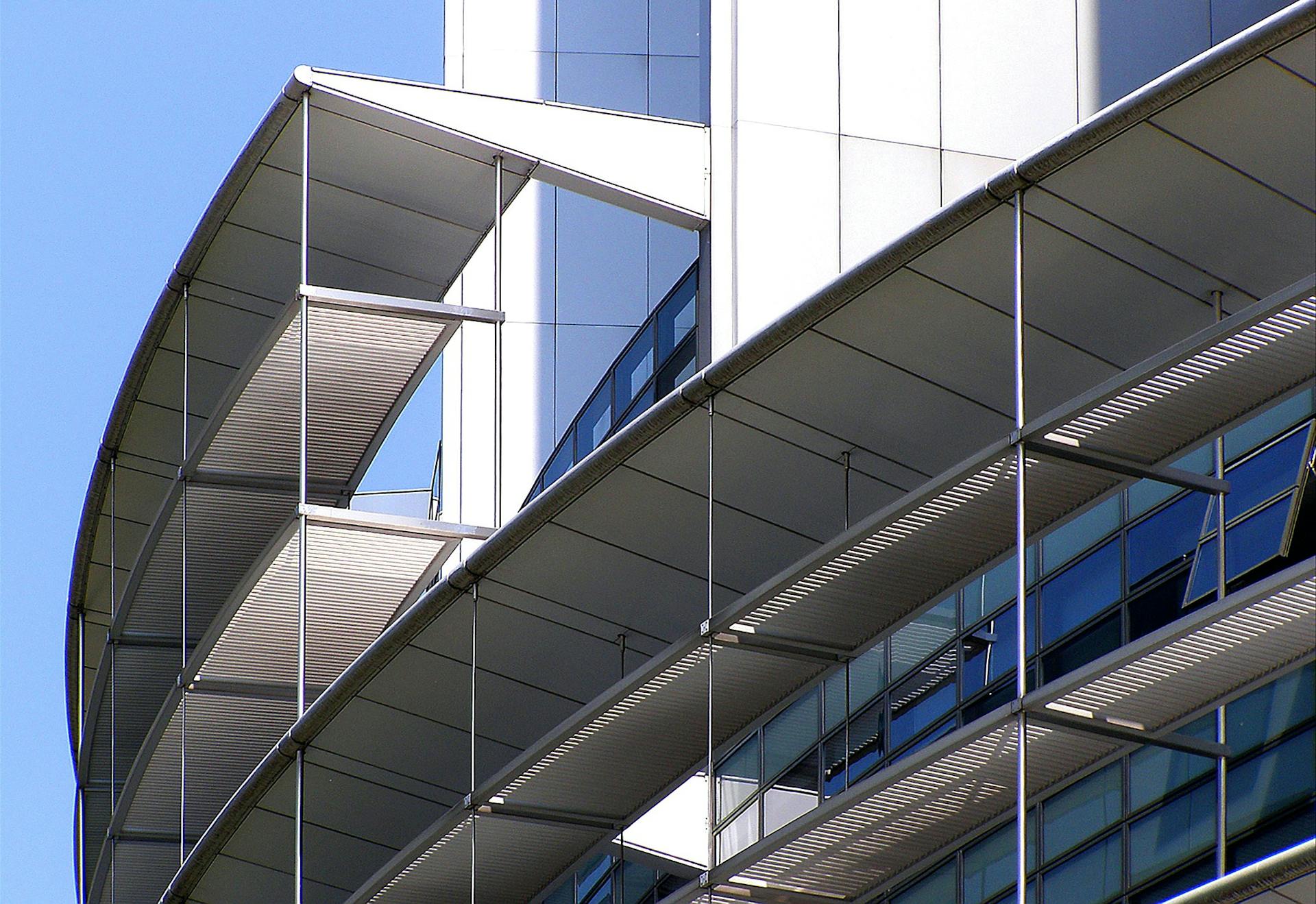 Close-up of a futuristic building facade with glass and metal elements reflecting modern architecture.