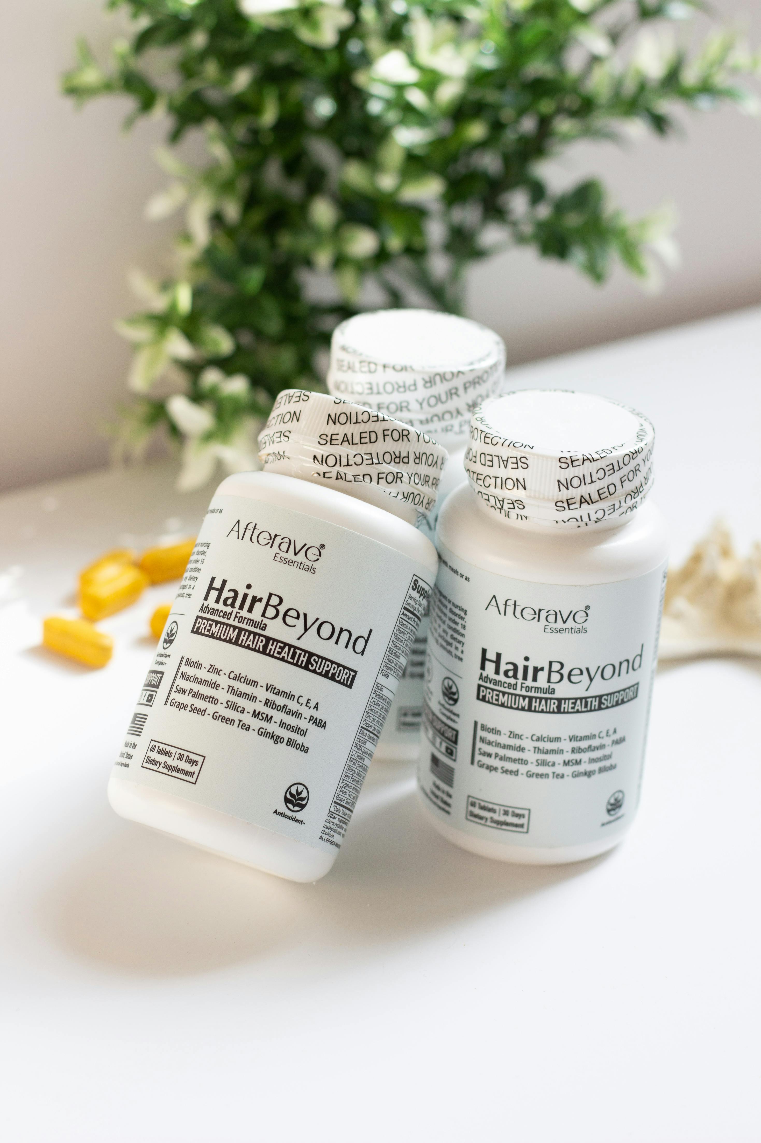Close-up of HairBeyond supplement bottles for hair health with natural ingredients on a light background.