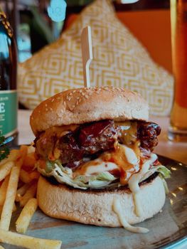 Juicy cheeseburger with fries served on a plate, surrounded by a cozy setting.