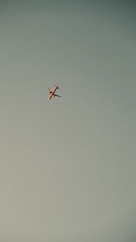 A distant airplane flying alone against a clear blue sky offering vast copyspace.