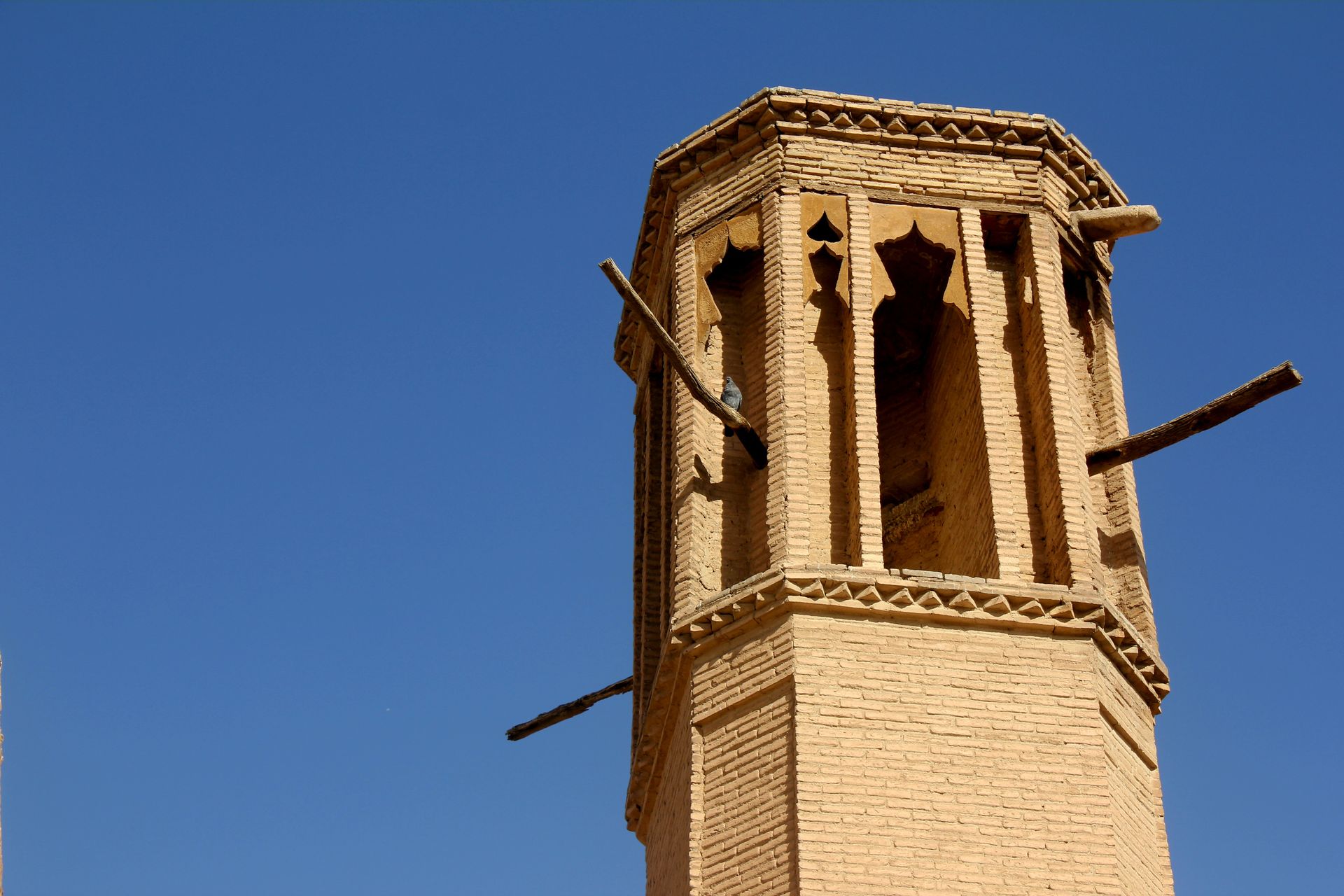 Close-up of a traditional wind tower architecture against a clear blue sky.