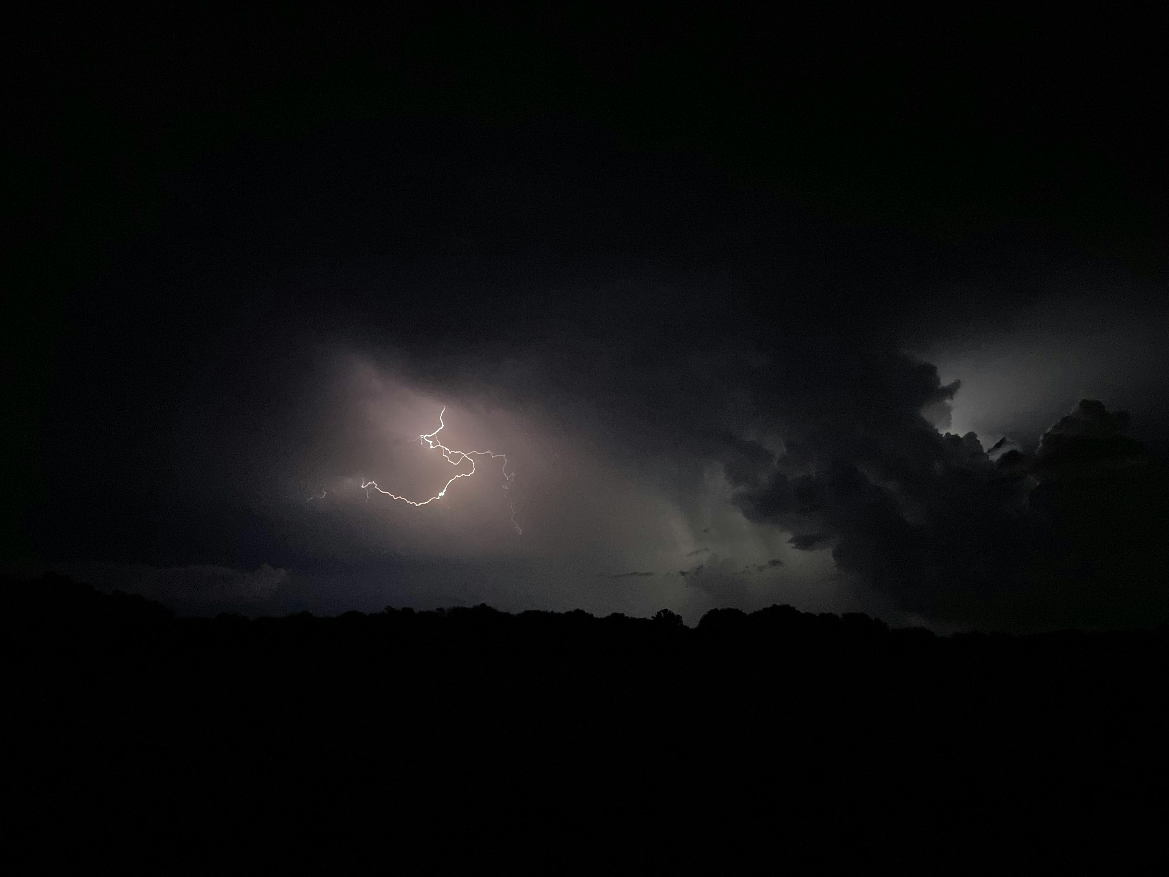 A striking lightning bolt illuminates a dark stormy night sky, creating a dramatic scene.