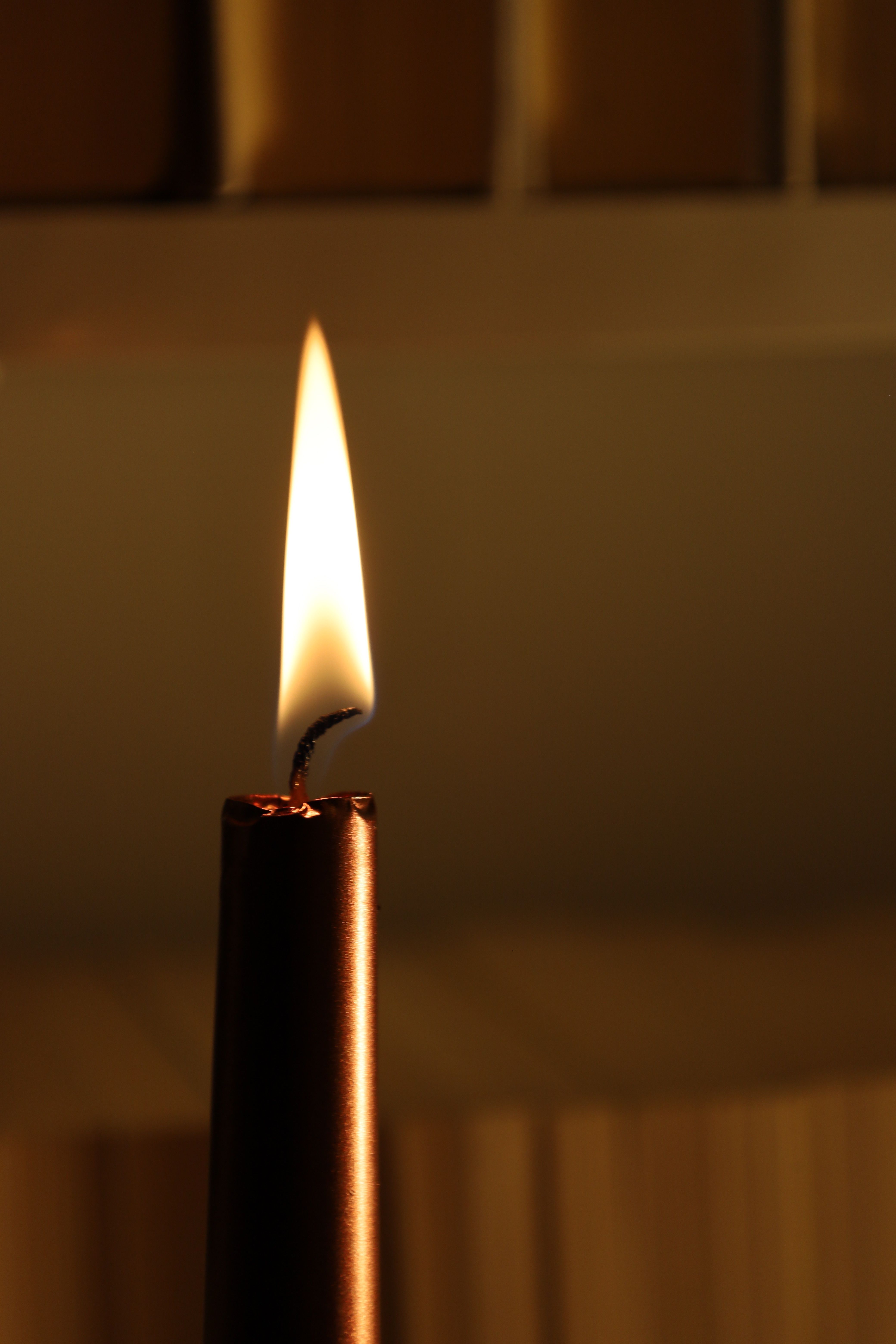 A glowing candle flame creates a warm, intimate atmosphere in a dark room.