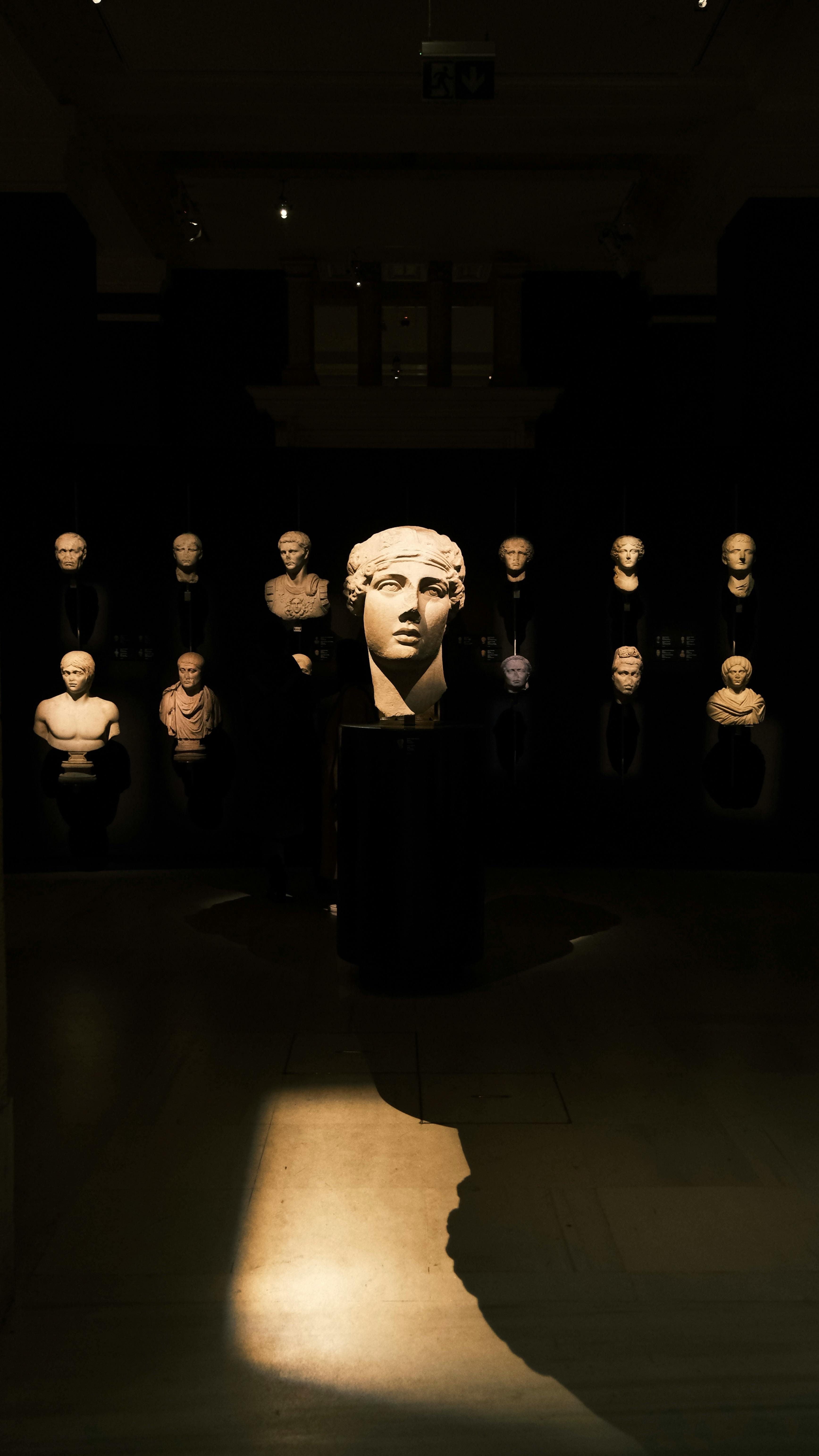 A dramatic view of ancient Roman busts in a dimly lit museum setting.