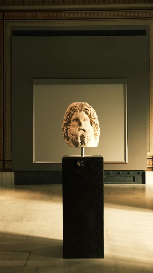 Free A classical sculpture bust displayed on a pedestal in a museum setting. Stock Photo