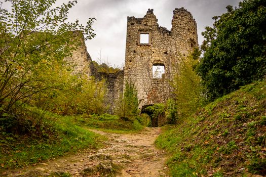 Explore the historic ruins of Samobor Castle surrounded by lush greenery under a cloudy sky.