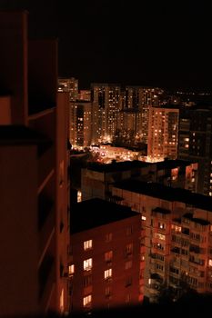 A high-rise cityscape at night with glowing windows and dim streetlights creating a warm, urban atmosphere.