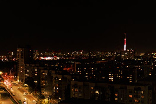 A breathtaking view of a city skyline at night, featuring a vibrant illuminated tower and buildings.
