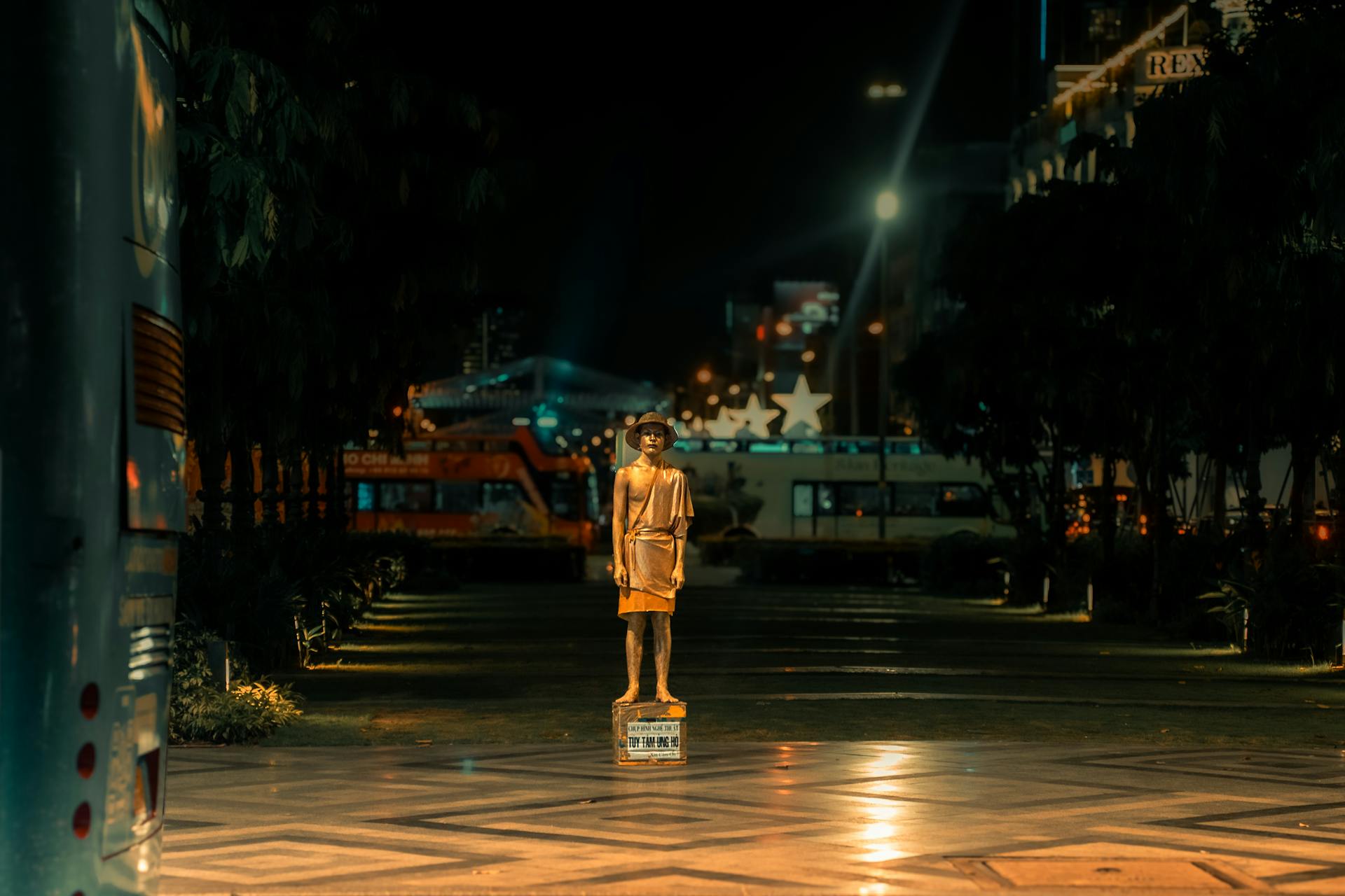 A street performer painted gold stands motionless at night in a city street.