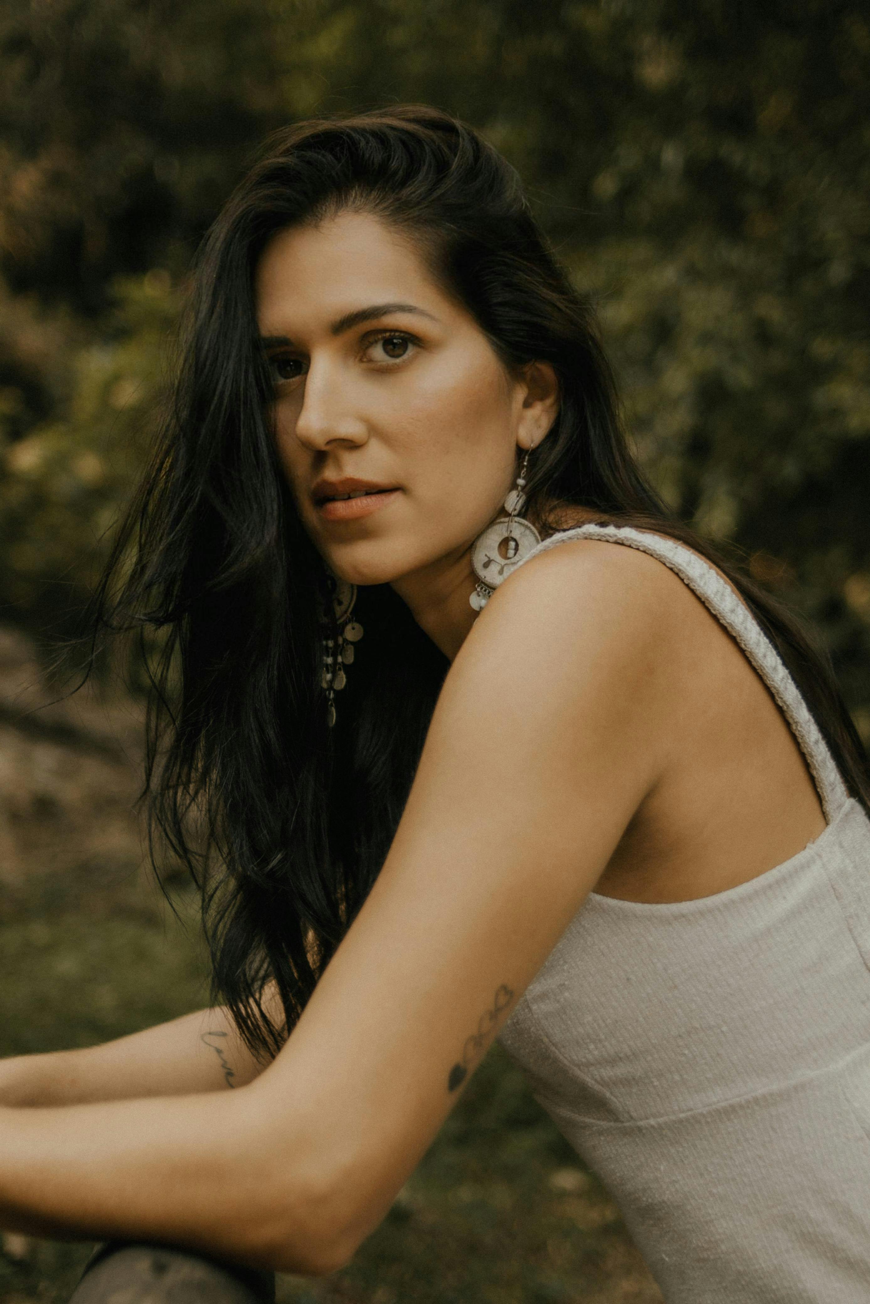 Close-up of a woman in a natural setting with soft lighting.