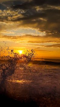 A mesmerizing sunset illuminates the ocean as waves crash on the shore, creating a dramatic seascape.