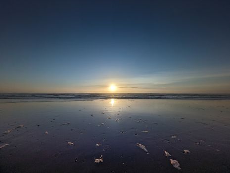 Peaceful sunset over the ocean with reflections on a calm beach. Perfect for tranquility and relaxation.