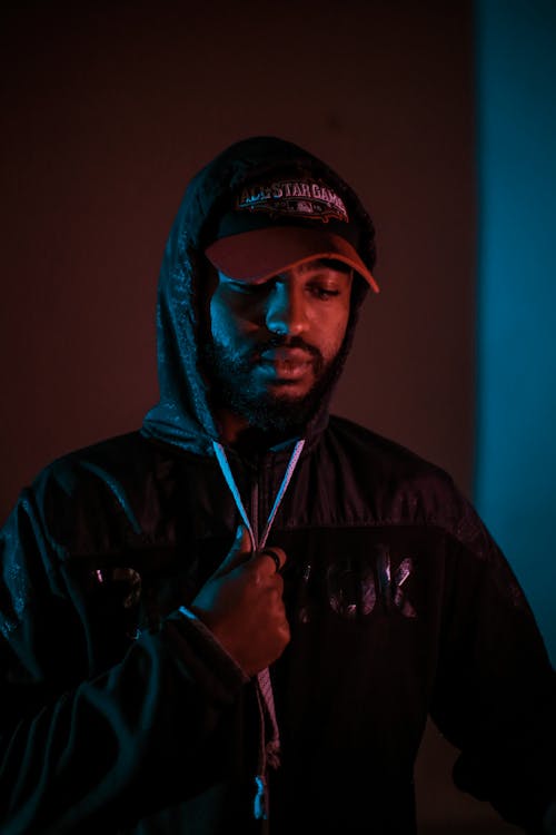 Photo of Man in Black Hooded Jacket  and Hat Posing While Looking Down