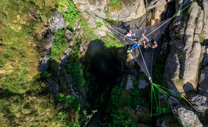 Adventure seekers crossing a rope net suspended above a rocky gorge — photo by Zak Bentley on Pexels