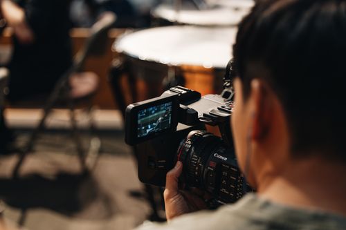 Free Filmmaker focuses intently as they capture video using a Canon camera in a studio setting. Stock Photo