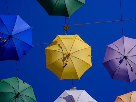 Vibrant umbrellas artistically suspended against a deep blue sky. Perfect for travel and lifestyle themes.