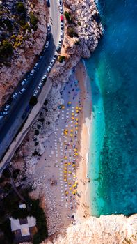 A vibrant aerial shot of a Mediterranean beach with sun loungers and turquoise waters.