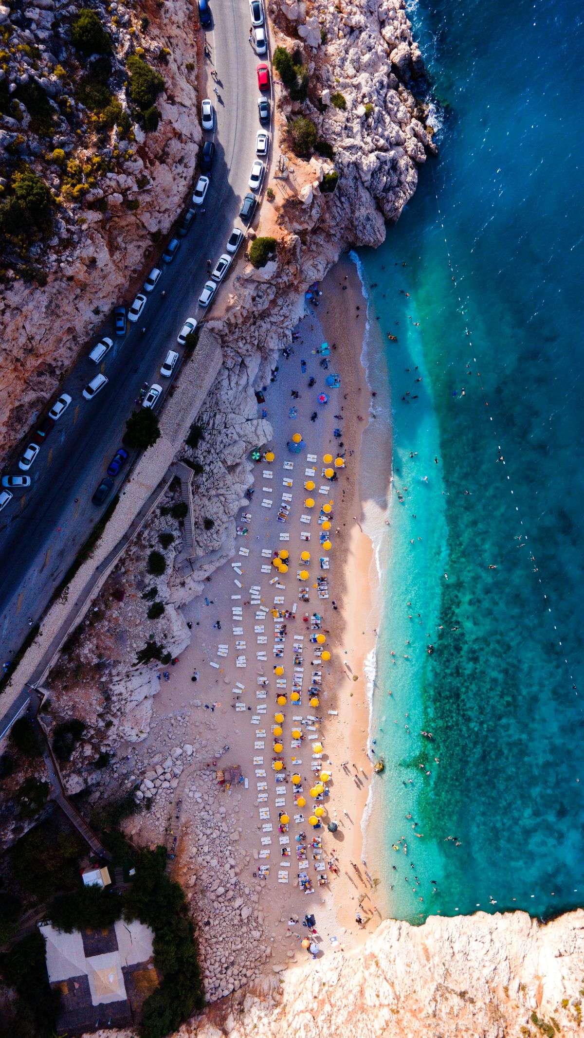Luftaufnahme einer mediterranen Bucht mit Liegestühlen und türkisblauem Wasser
