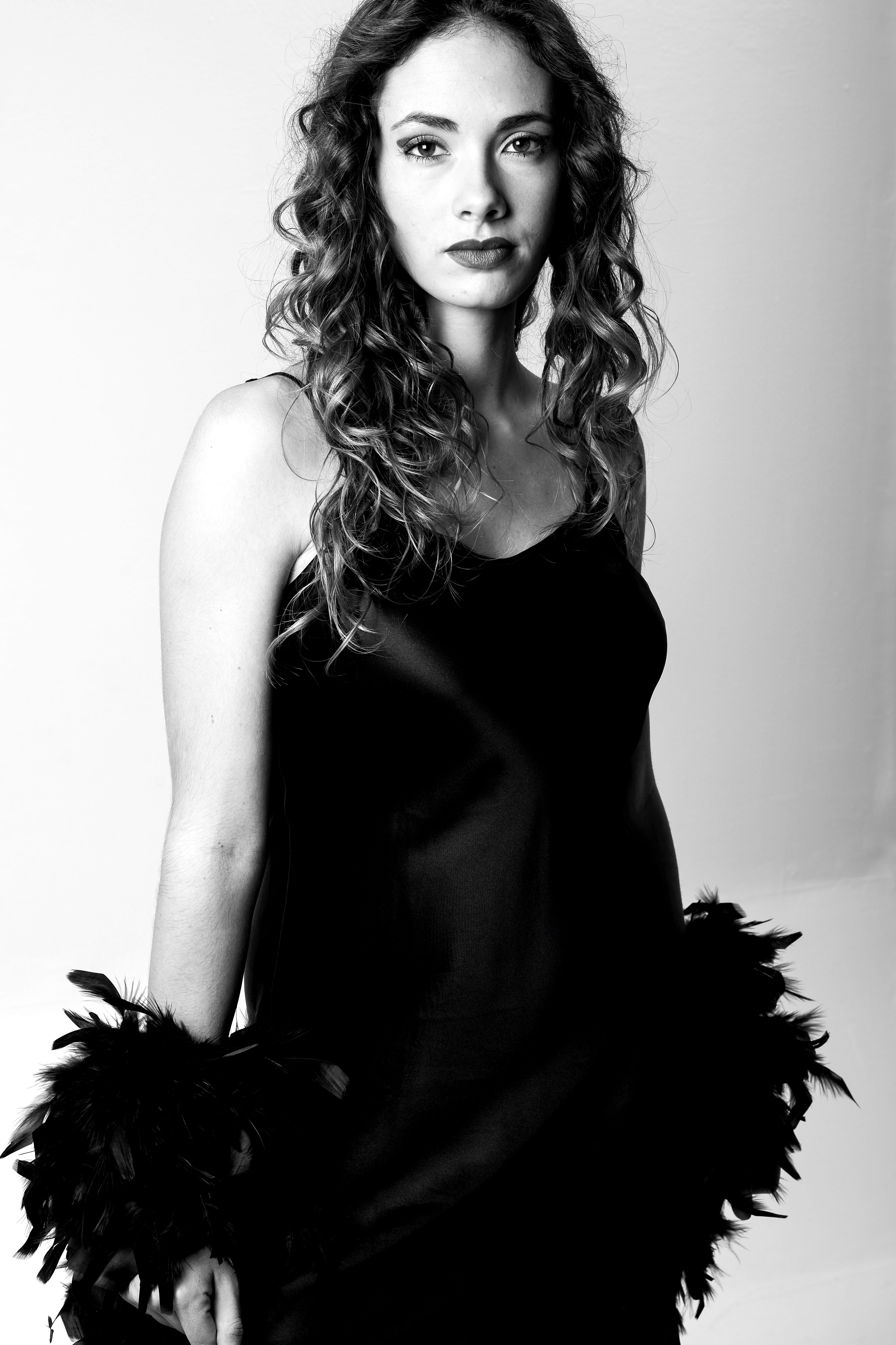 Black and white portrait of an elegant woman in a dress with feather details, exuding classic style.