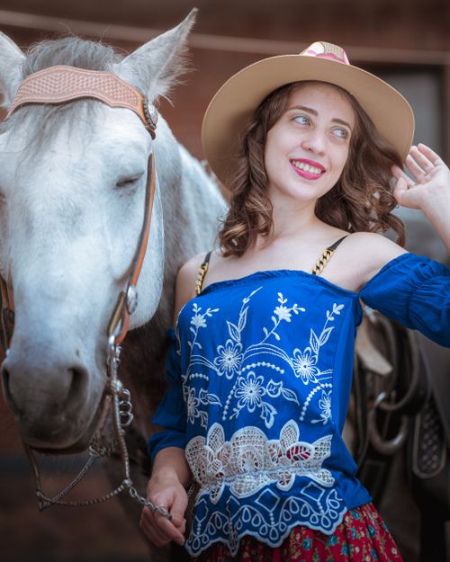 Free Young woman in cowboy hat smiling beside a white horse outdoors. Stock Photo
