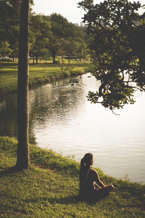 女人坐在湖邊的草地上