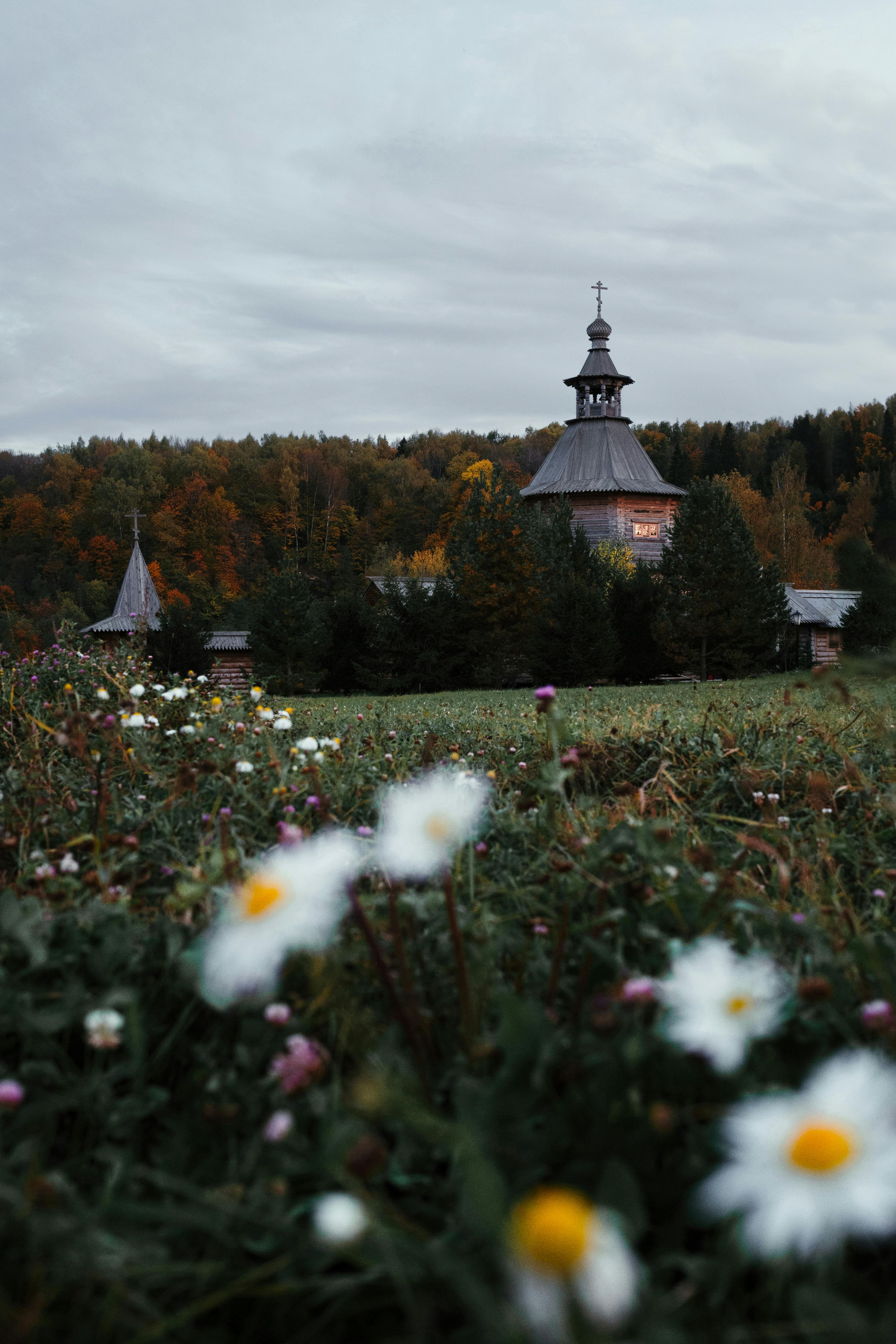 A serene autumn landscape featuring a wooden church surrounded by a lush forest.