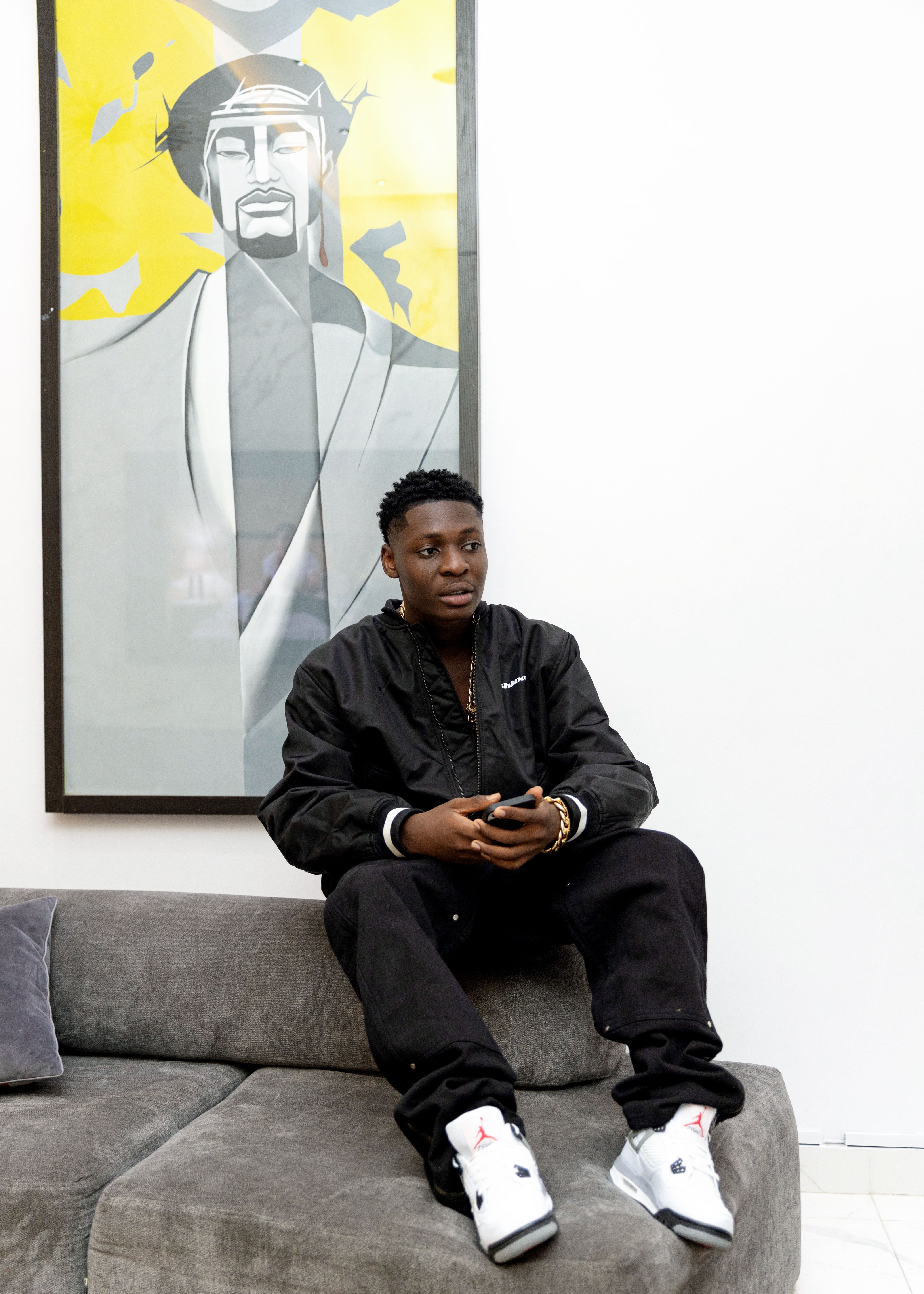 Man sitting on sofa in stylish interior with modern art on wall.