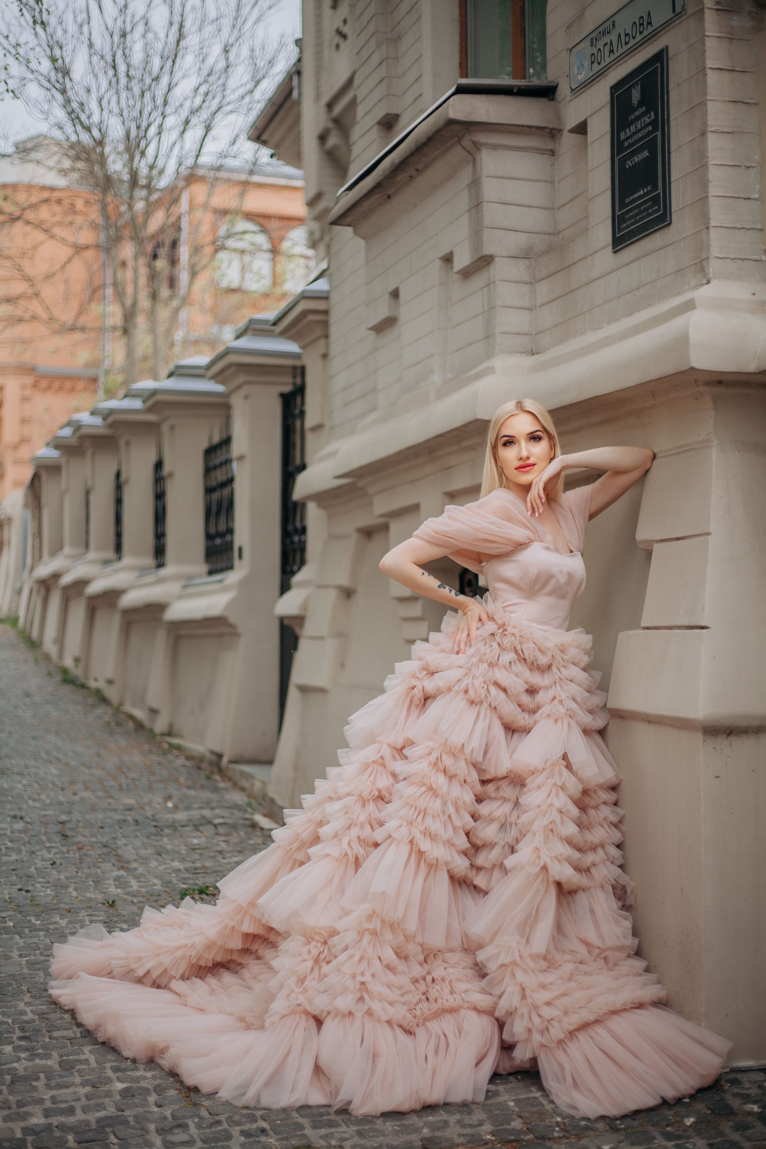 Elegant Woman in Pink Gown Against Urban Backdrop