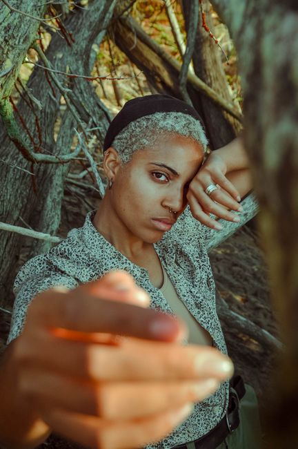 Captivating portrait of a woman posing among tree branches, exuding a strong and confident presence.
