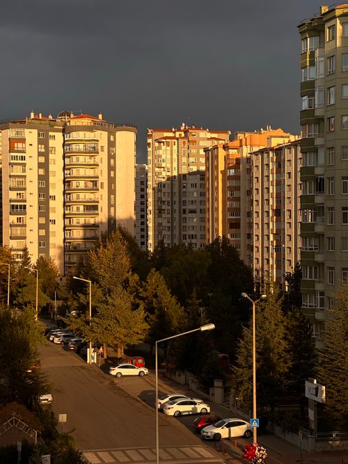 Free A dramatic urban residential area with sunlit buildings against a dark sky at dusk. Stock Photo