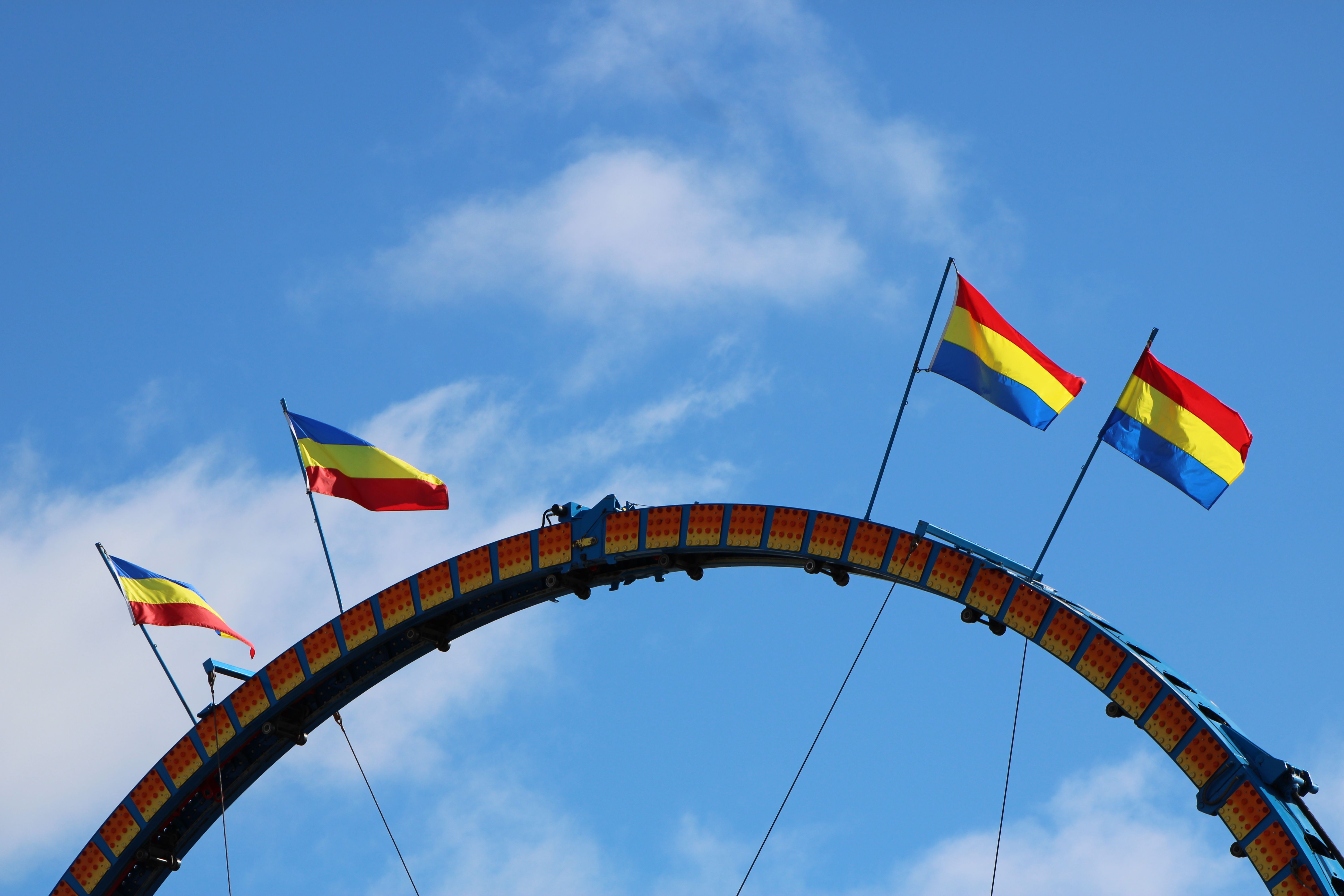 Flags on Amusement Park Ride Against Blue Sky · Free Stock Photo