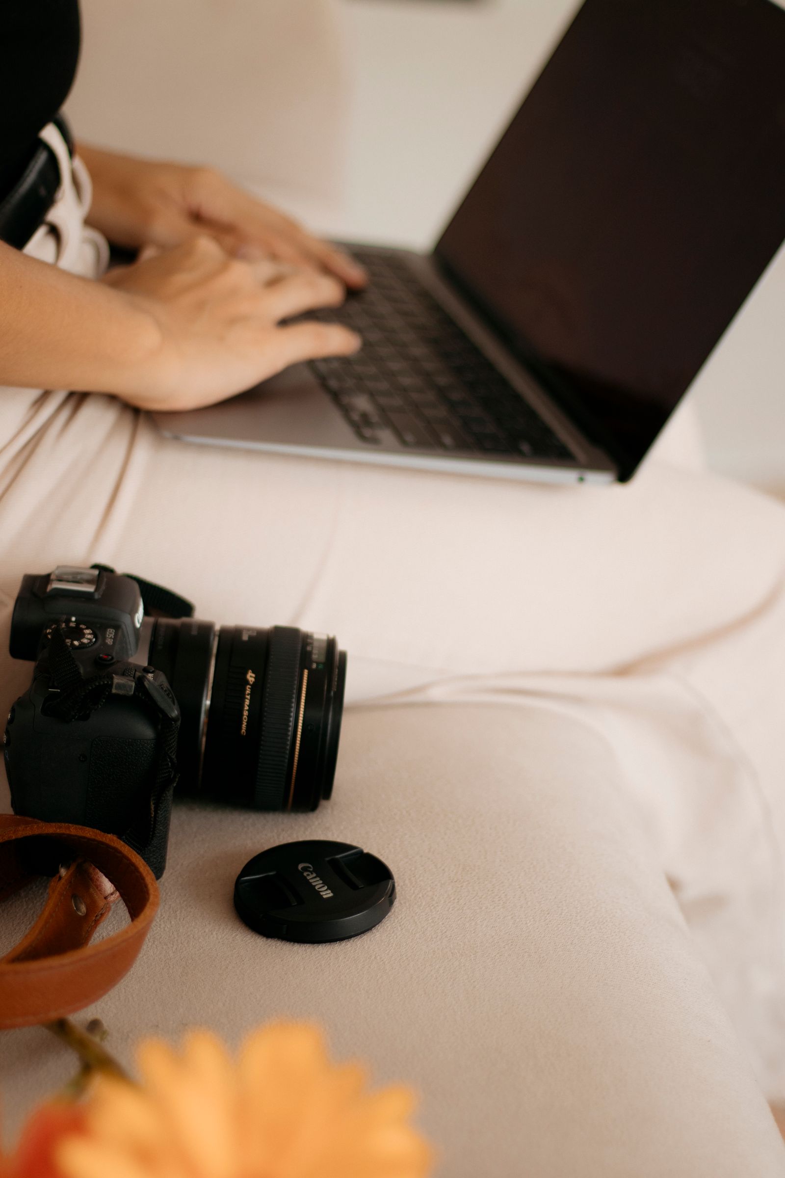 A photographer editing photos on a laptop with a camera nearby